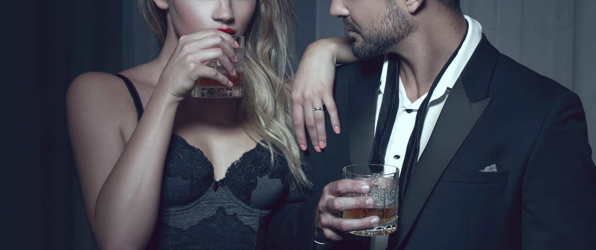 Stilvolle Frau in Lingerie genießt mit Begleiter einen Drink im Club.